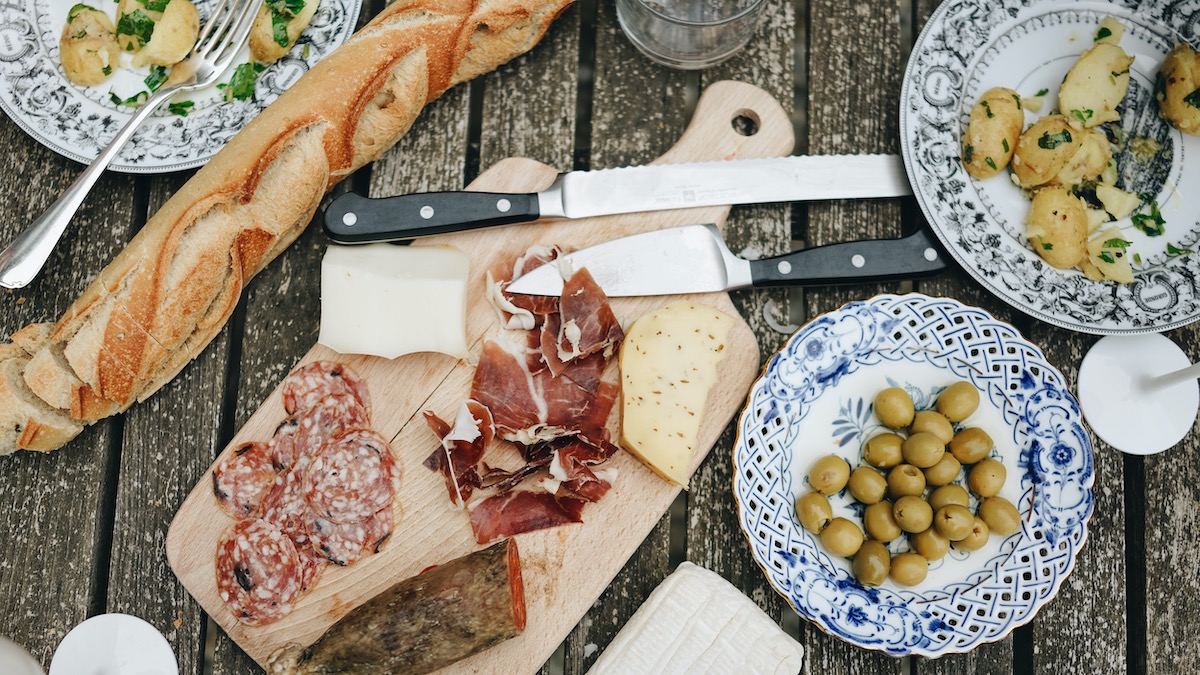 Wine Pairing Dinner Table With Meats, Cheeses, Olives, Potatoes, And Bread